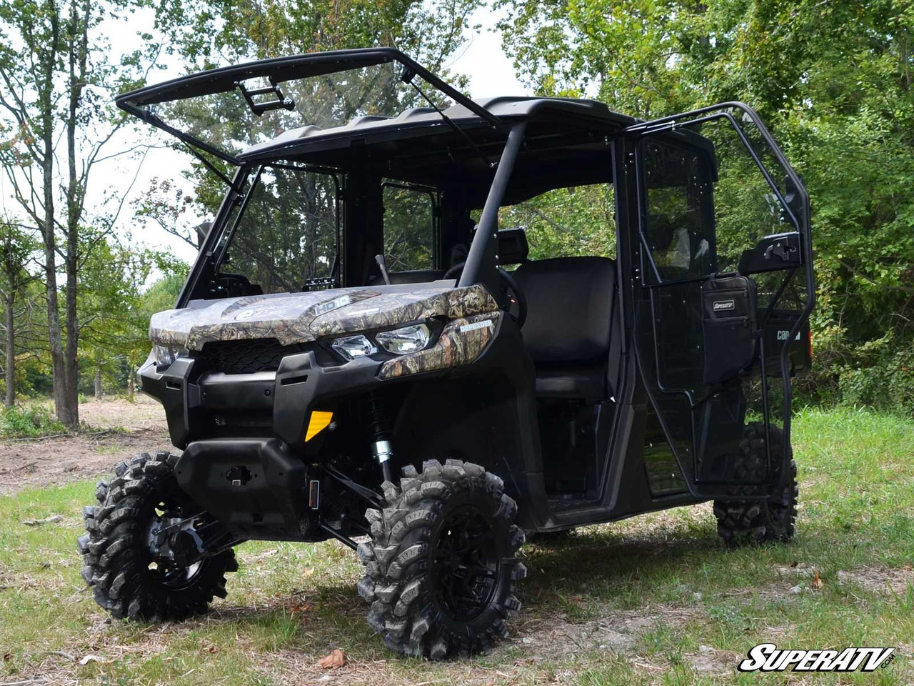 Camo Can-Am Defender Max with all four SuperATV cab doors installed and mud tires, front three-quarter view in a field
