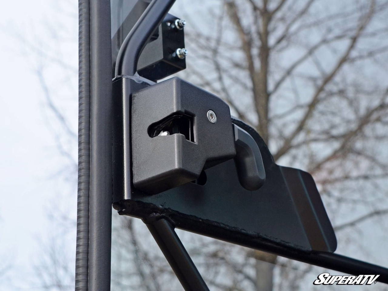Close-up of the SuperATV door hinge and latch bracket bolted to the Can-Am Defender cab frame