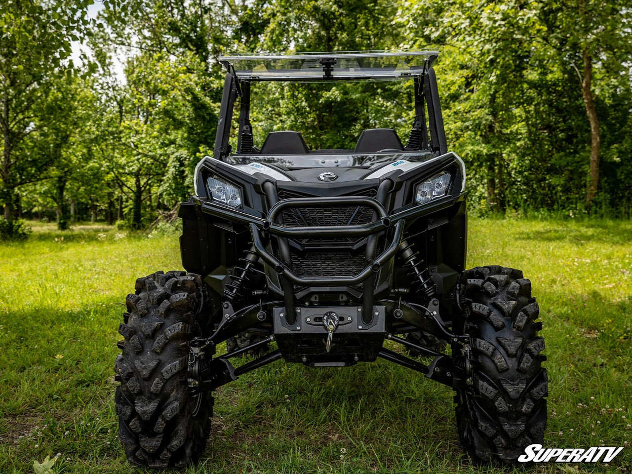 SuperATV winch mounting plate fitted to a lifted Can-Am Maverick Trail, front view on a grassy trail