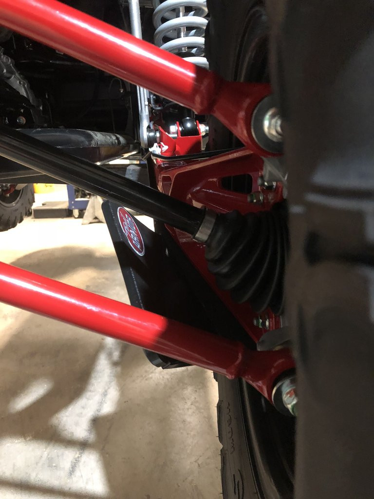 Close-up of a Trail Armor guard bolted to the red trailing arm behind the rear wheel of a Honda Talon 1000 X