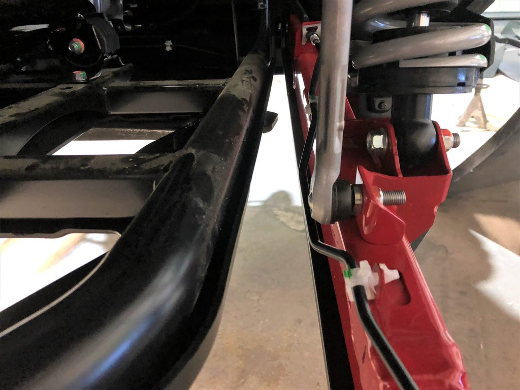 Close-up of the Trail Armor guard front mounting bolt at the trailing arm pivot of a Honda Talon 1000 X