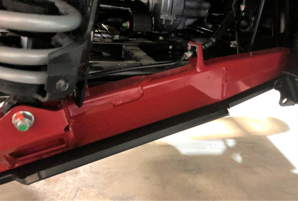 Side view of the Trail Armor guard running the full length under the red trailing arm of a Honda Talon 1000 X