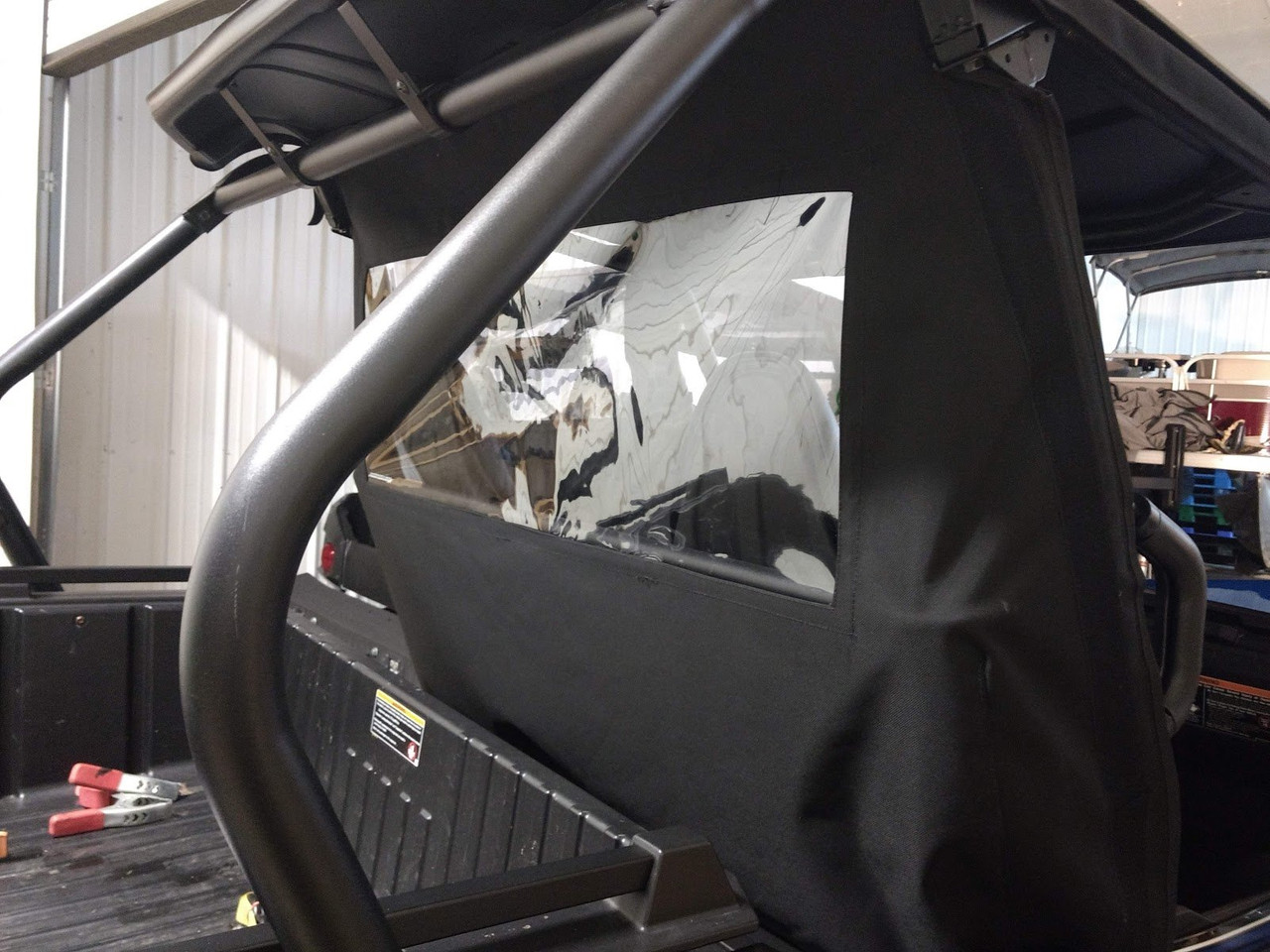 Side X Side rear window panel with clear vinyl seen from the bed of a Kawasaki Teryx 2 in a shop