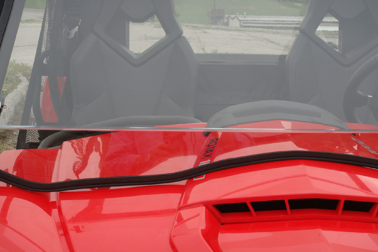 3 Star two-piece windshield lower edge with rubber seal on a red Can-Am Commander hood, seats seen through the glass