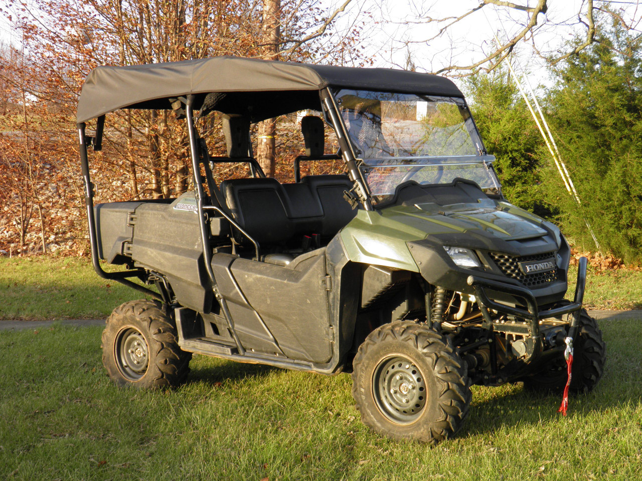 3 Star black soft top installed on a green Honda Pioneer 700-4, front three-quarter view in a field