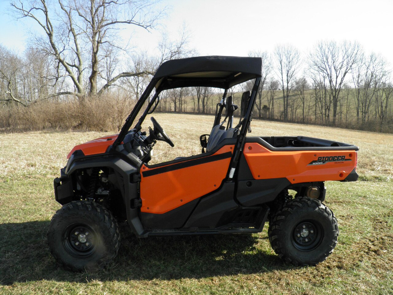 Driver side profile of an orange Honda Pioneer 1000 with the 3 Star soft top installed