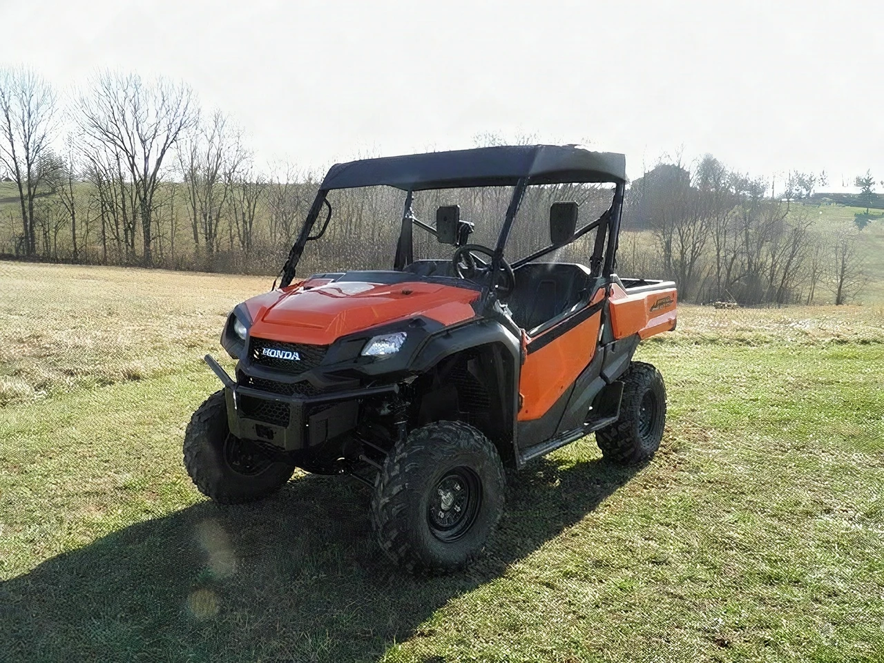 3 Star black soft top on an orange Honda Pioneer 1000, front three-quarter view in a field