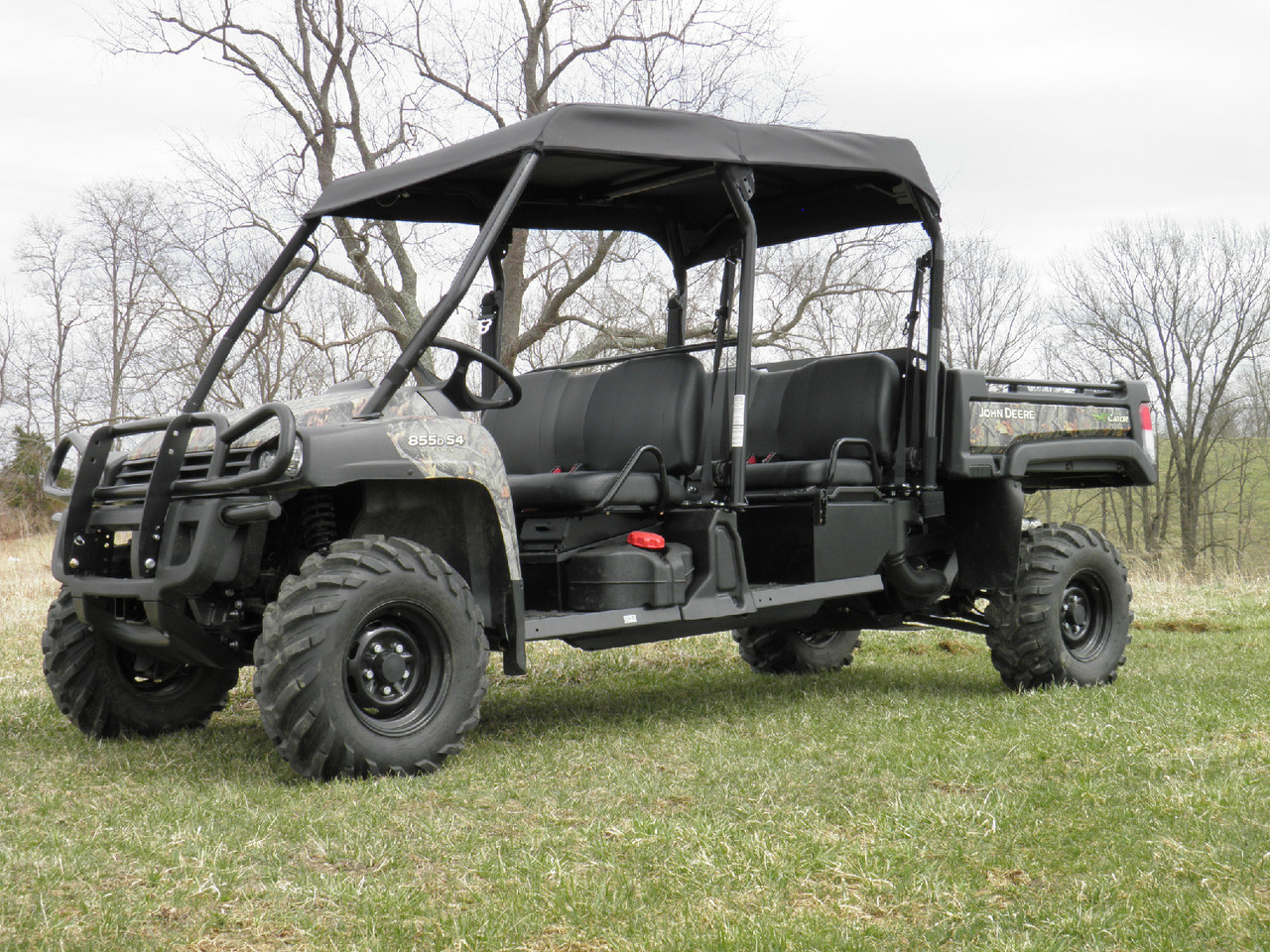 Passenger side view of the camo John Deere Gator XUV-4 with the 3 Star soft top and cargo bed