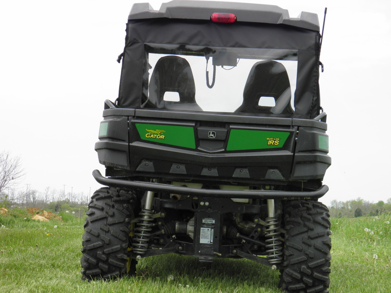 Straight rear view of the 3 Star cab enclosure clear rear window on a green John Deere Gator with the seats visible