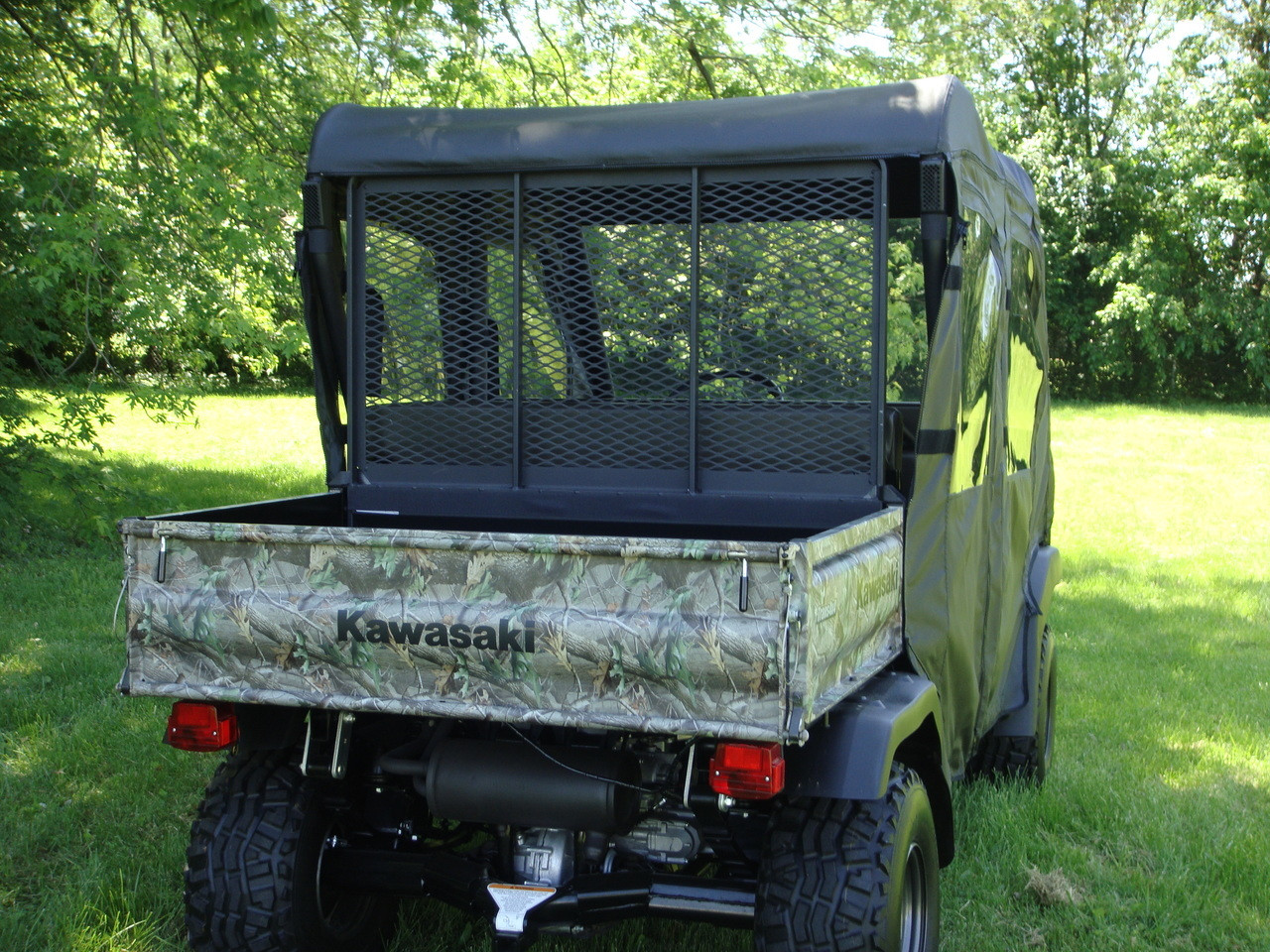 Rear view of a camo Kawasaki Mule 3000/3010 Trans with the 3 Star soft back panel rolled up over the mesh
