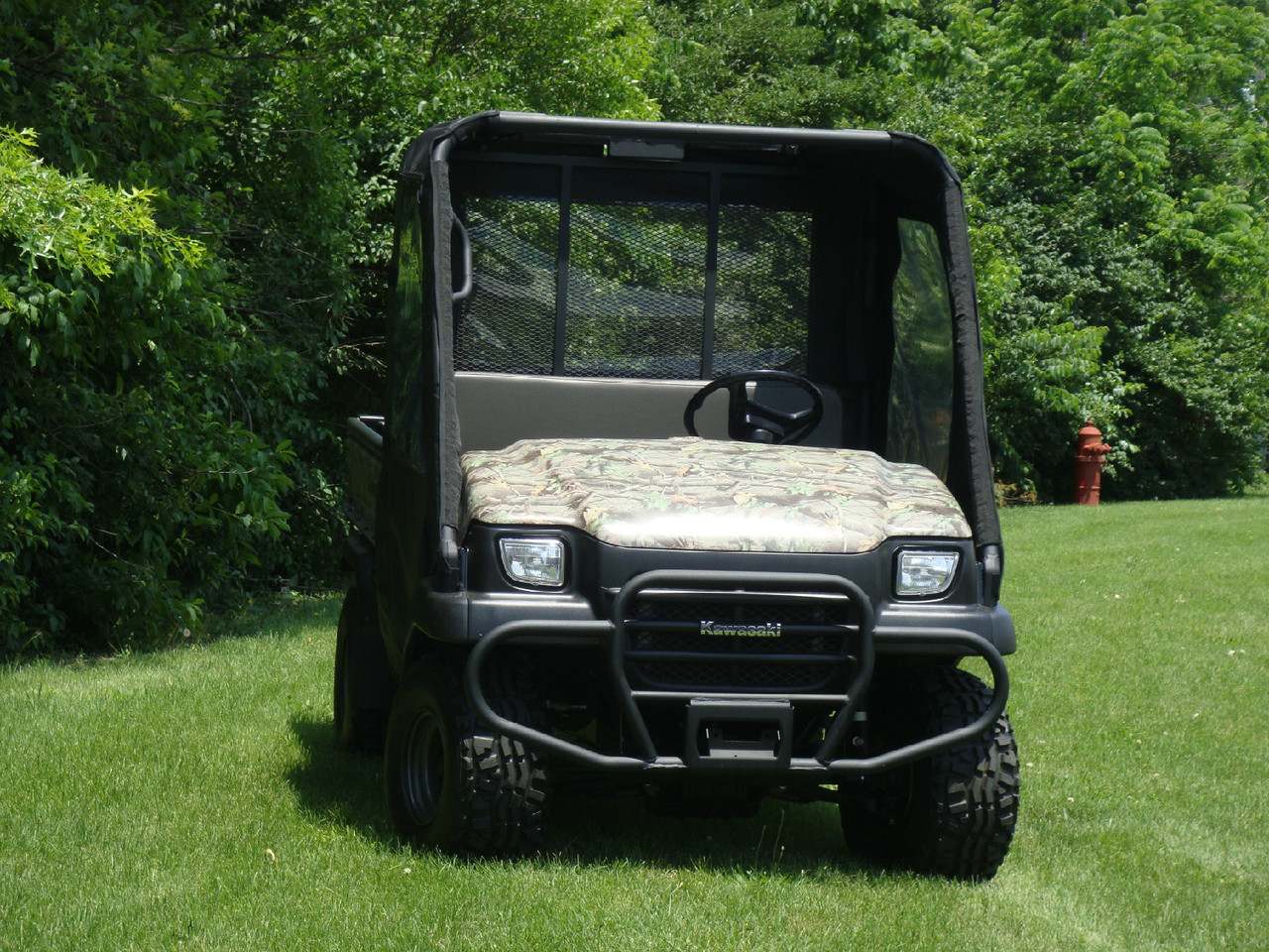 Front view of a camouflage Kawasaki Mule SX with the 3 Star cab enclosure and hard windshield