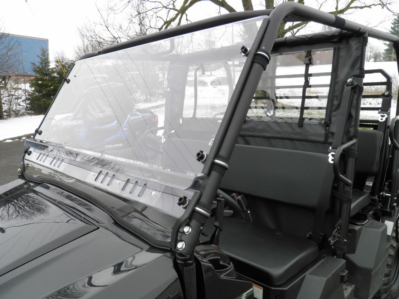 Side angle of the 3 Star 2-piece windshield on a Kawasaki Mule ProFX showing the cage clamps and cab interior