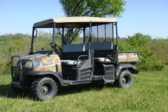 Side view of the camo Kubota RTV1140 with the 3 Star tan soft top covering both rows of seats