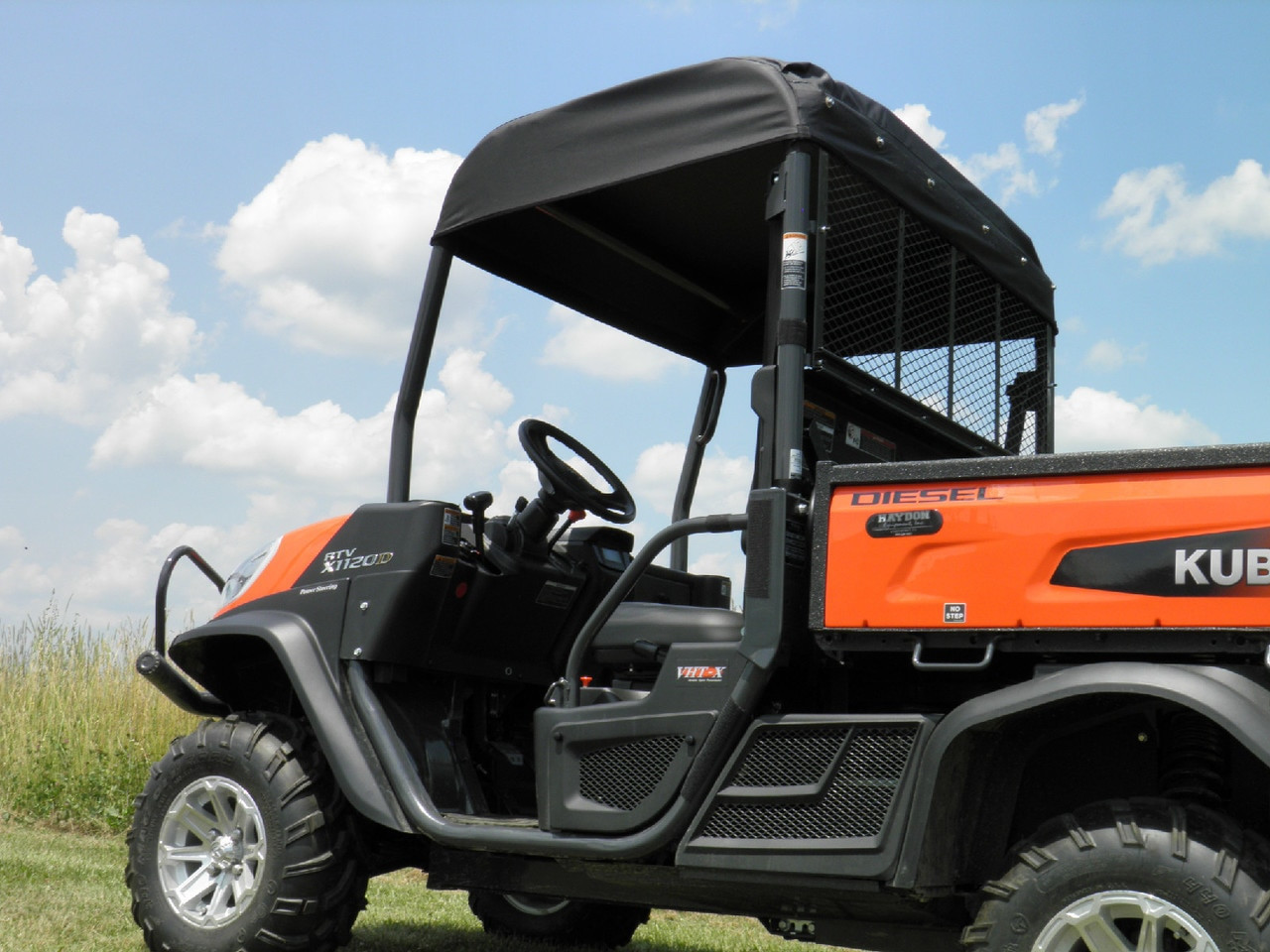 Low-angle side view of the 3 Star Kubota RTV X900/1120 soft top shading the cab against a blue sky