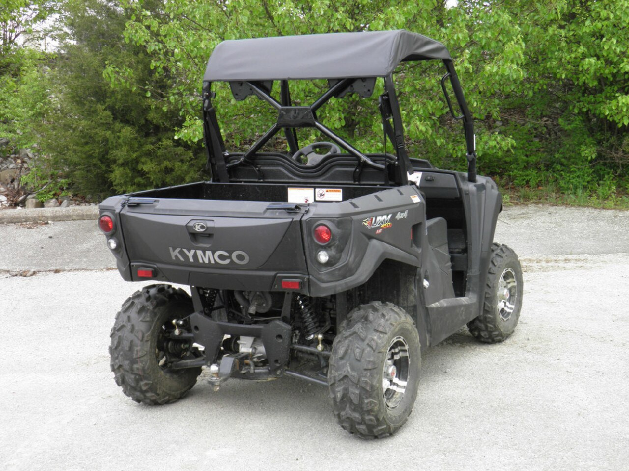 Rear three-quarter view of the gray Kymco 450 with the 3 Star soft top, Kymco tailgate visible