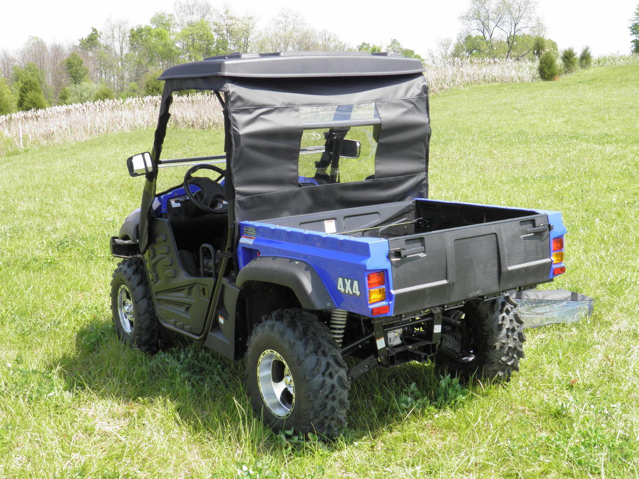 Rear three-quarter view of the 3 Star soft rear window panel above the cargo bed of a blue side-by-side