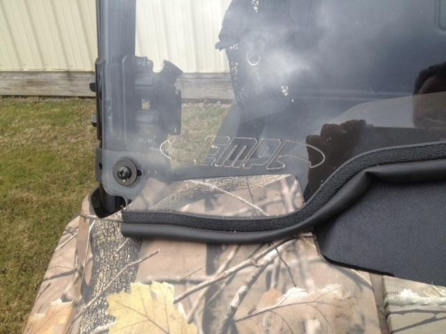 Close-up of the Extreme Metal Products windshield edge with EMP logo, rubber seal and cage clamp on the camo Pioneer 700