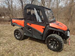 Side X Side upper doors kit installed on an orange Intimidator GC1K with full soft cab, front three-quarter view