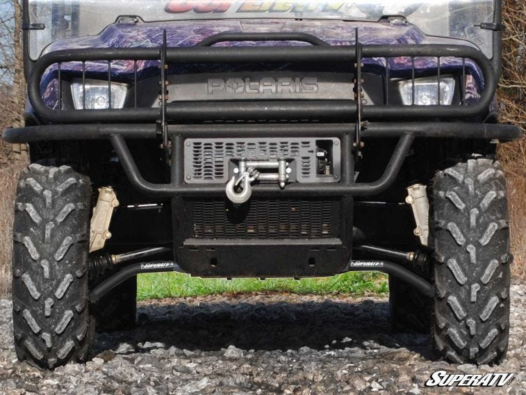 Front view of SuperATV high clearance A-arms installed on a side-by-side with a winch bumper on rocky ground