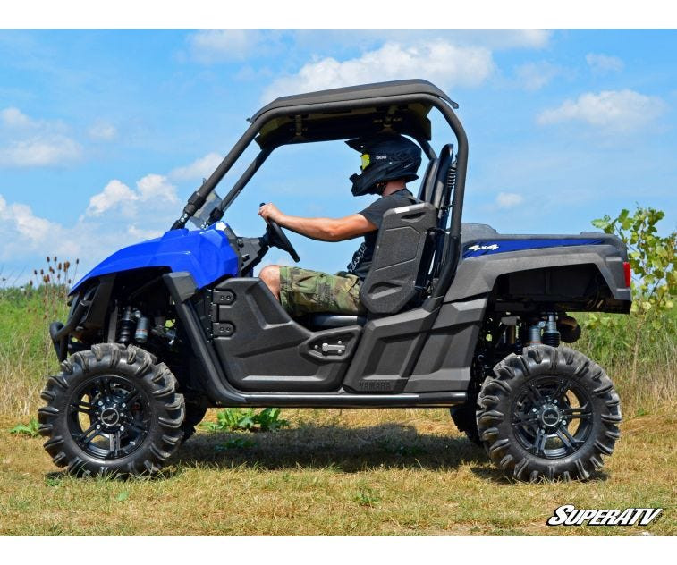 Side profile of a blue Yamaha Wolverine with the SuperATV 2-inch lift kit and mud tires, driver seated