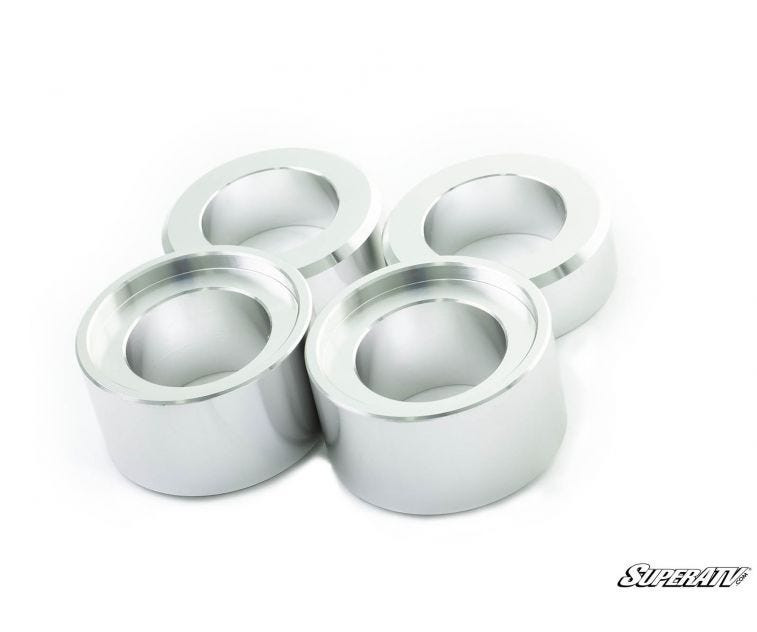 Four machined aluminum spacers from the SuperATV Kubota RTV X Series 2 inch lift kit on white