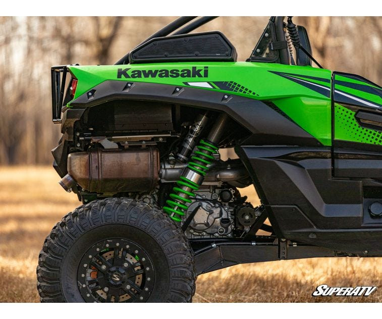 Rear wheel close-up of the lifted green Kawasaki Teryx KRX 1000 showing the SuperATV lift kit shock spacer and tire
