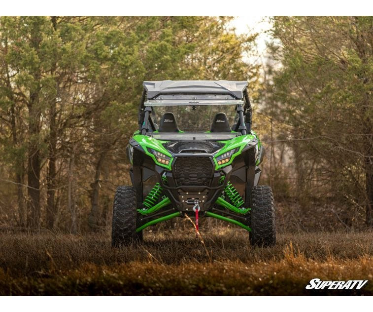 Front view of the green Kawasaki Teryx KRX 1000 with the SuperATV 3-inch lift kit installed, in a wooded field
