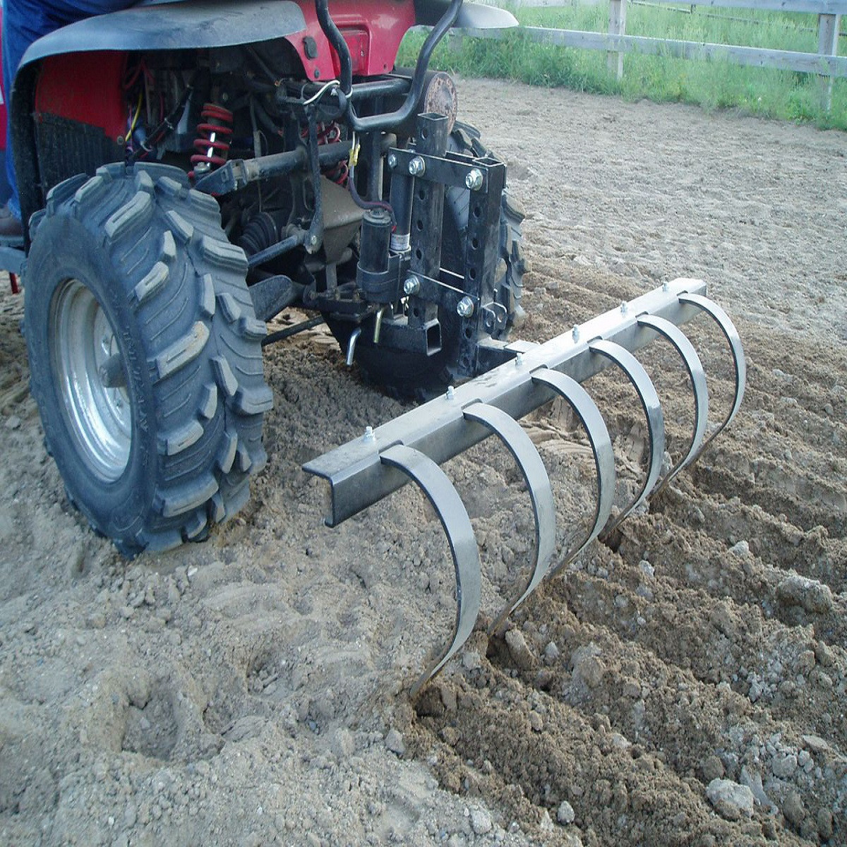 Moto Alliance IMPACT Pro cultivator being pulled behind an ATV through tilled soil, rear view
