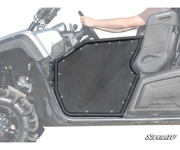 SuperATV aluminum door closed on a Yamaha Viking with the driver resting an arm on the top rail, side view