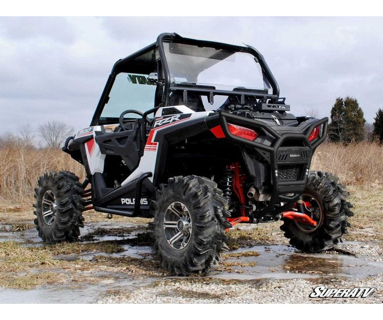 SuperATV rear bumper installed on a white Polaris RZR 1000 S with mud tires, rear three-quarter view in mud