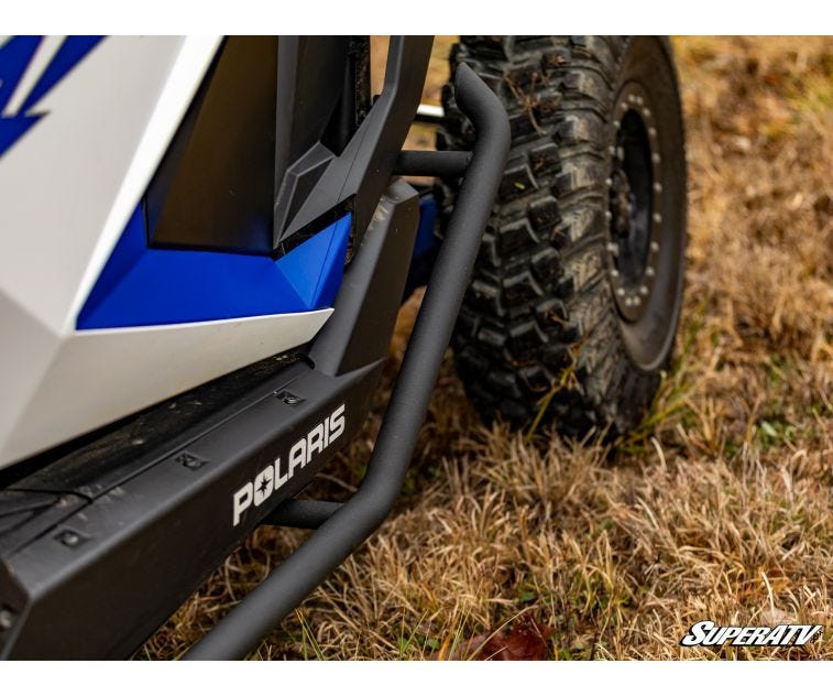 Close-up of the SuperATV nerf bar end near the rear tire of a Polaris RZR Pro XP in dry grass