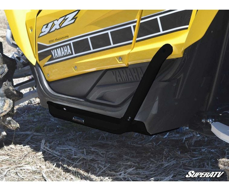 Close-up of the SuperATV heavy duty nerf bar mounted below the door of a yellow Yamaha YXZ