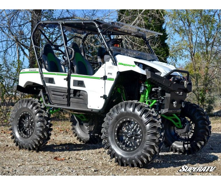 White Kawasaki Teryx 4 with SuperATV heavy duty nerf bars, front three-quarter view on a gravel lot