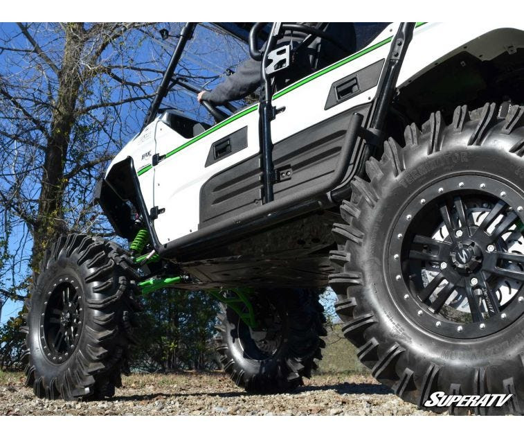 Low angle of the SuperATV nerf bar along the rocker of a white Kawasaki Teryx 4 with aggressive mud tires