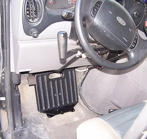 Sure Grip gas and brake guard mounted on the floor of a car in front of the pedals below the steering wheel