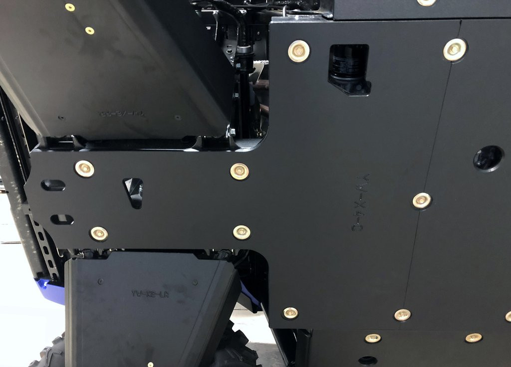 Underside view of the Trail Armor full skid plate bolted to the frame of a Yamaha Wolverine X4 beside the wheel