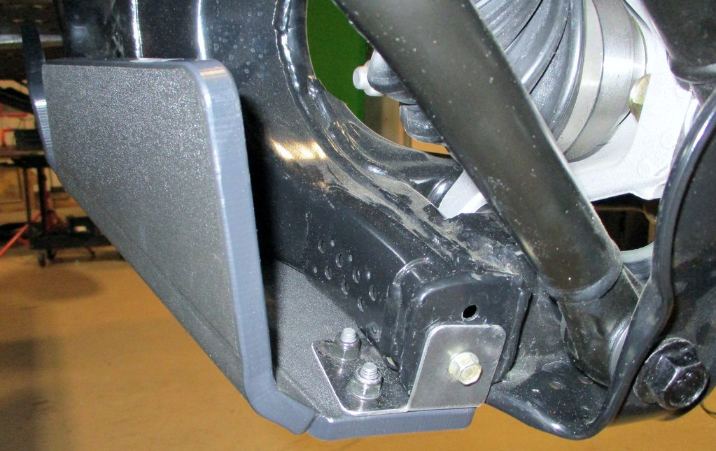 Close-up of a gray Trail Armor trailing arm guard wrapped around the arm end near the CV joint