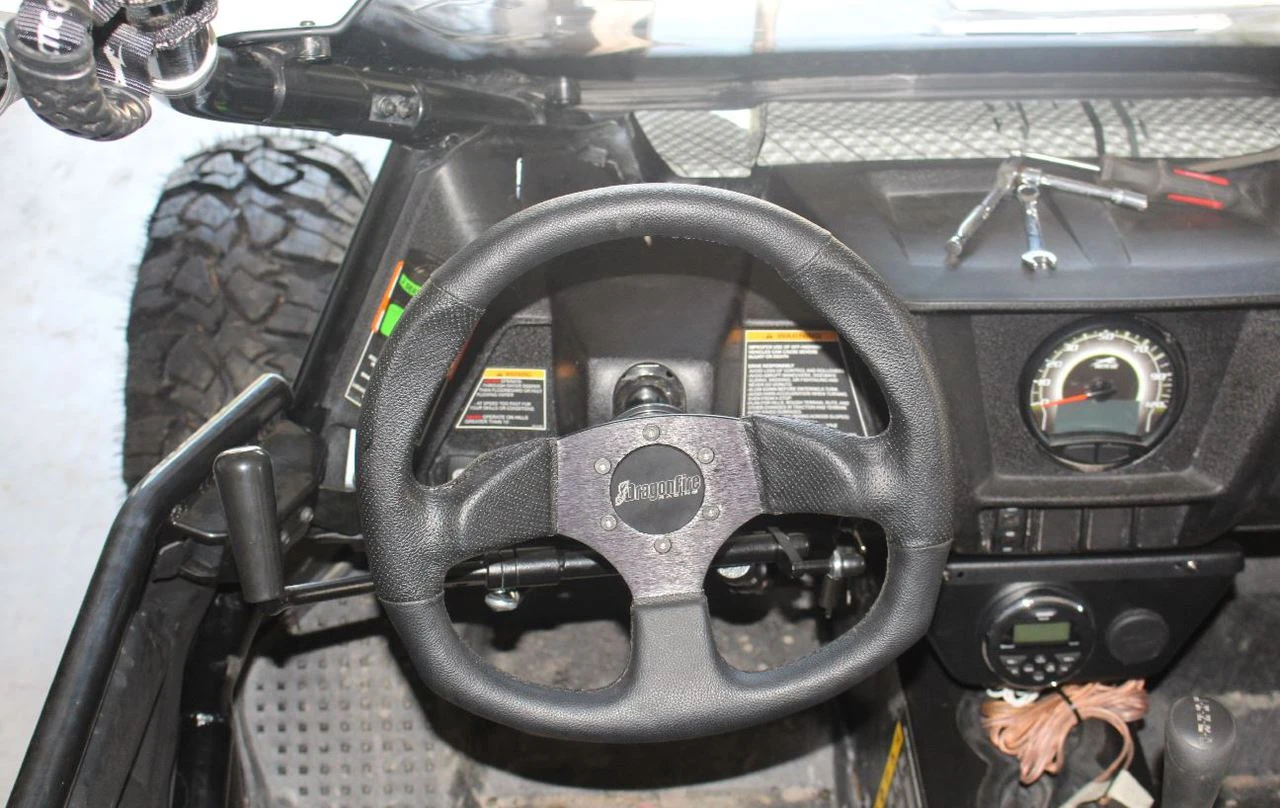 Sure Grip hand control lever mounted beside the steering wheel inside the cab of an Arctic Cat Wildcat, driver view