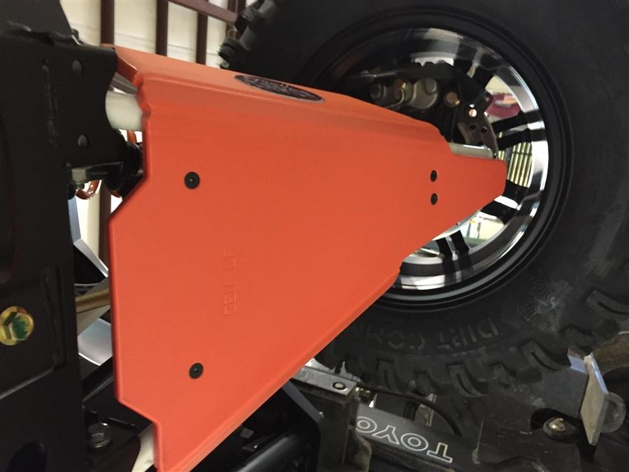 Close-up of an orange Trail Armor rear A-arm guard installed behind the wheel of a Polaris General 1000