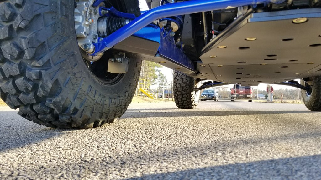 Trail Armor iMpact trailing arm guard installed under a blue Polaris RZR XP Pro, low angle beside the rear tire