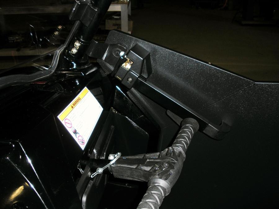 Close-up of the Trail Armor debris shield latch bracket and cable on the Polaris RZR door frame