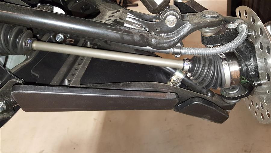 Close-up of a black Trail Armor A-arm guard under the front lower A-arm and CV axle of a Yamaha Wolverine