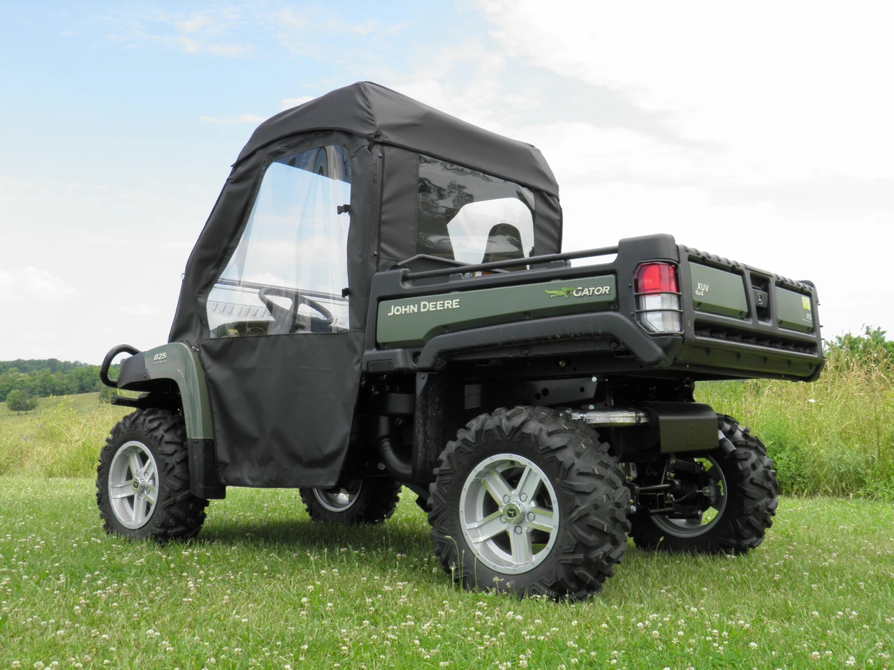 Rear three-quarter view of the 3 Star full cab enclosure on the green John Deere Gator showing the rear window and bed