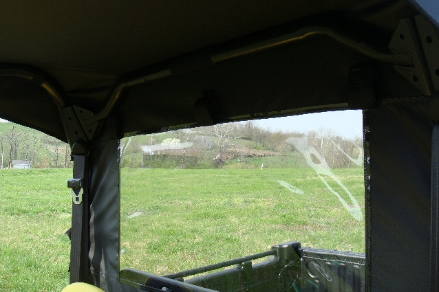 View from inside the cab through the 3 Star enclosure clear rear window toward the John Deere Gator cargo bed
