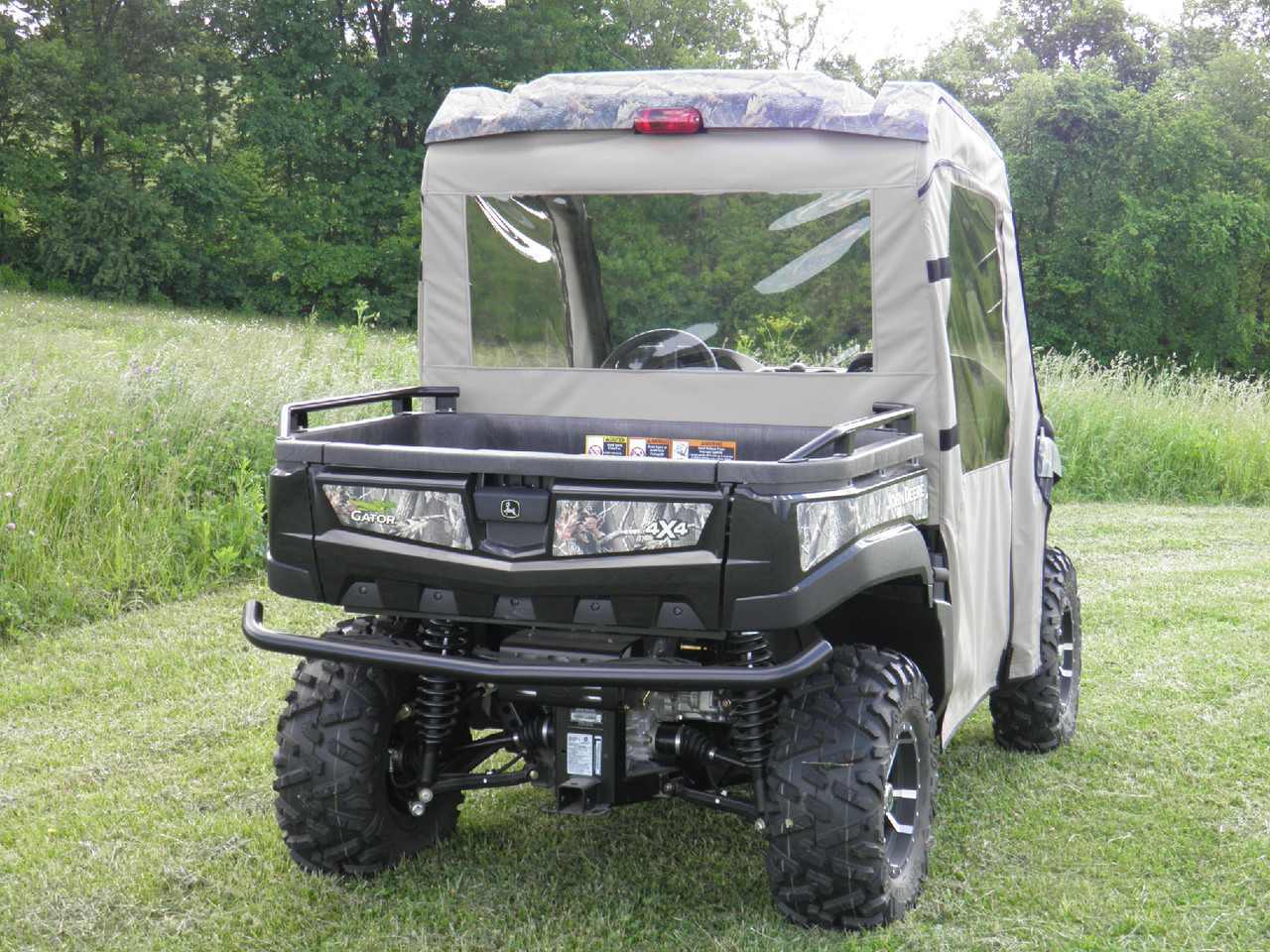 Straight rear view of the camo John Deere Gator with the 3 Star tan enclosure showing the clear rear window and taillights