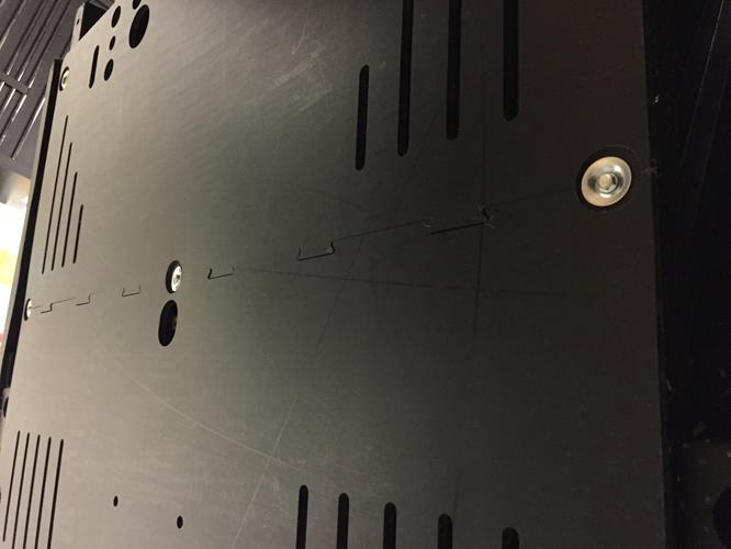 Close-up of the black Universal Parts UHMW skid plate with slotted cooling cutouts and a flush countersunk bolt