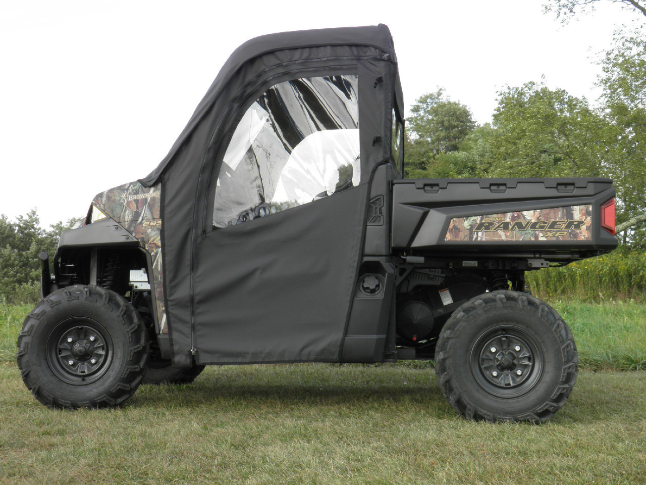 Driver side profile of the camo Polaris Ranger with the 3 Star soft enclosure doors and clear windows in a field