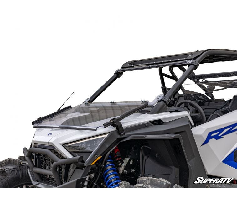 SuperATV flip down windshield folded forward over the hood of a white Polaris RZR PRO XP, front three-quarter view