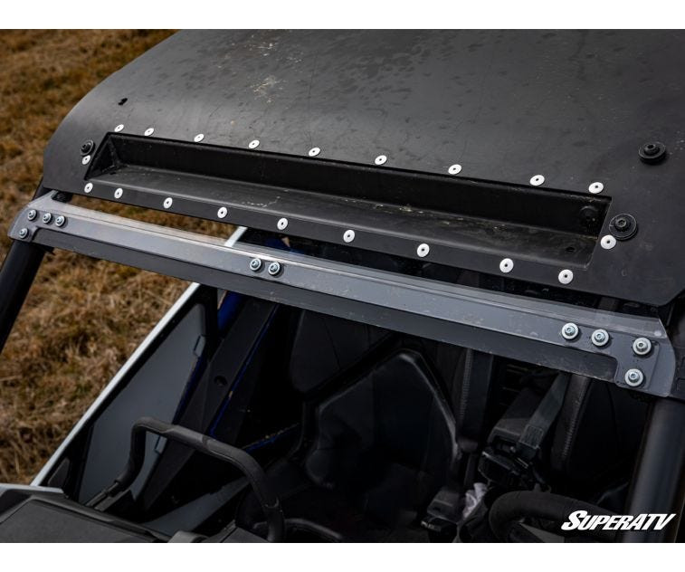 Close-up of the SuperATV windshield upper mounting bracket and roof clamp bar on a Polaris RZR PRO XP
