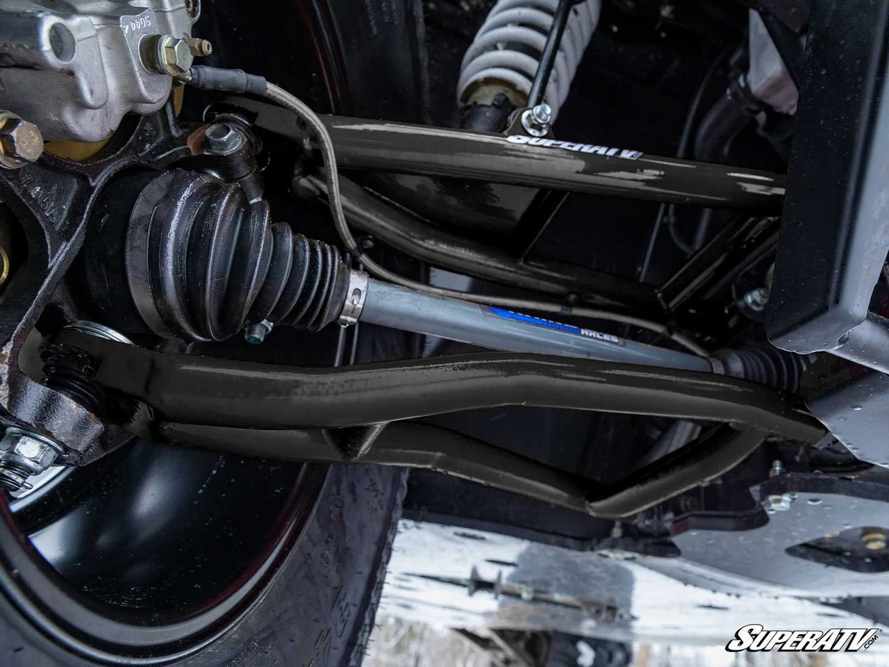 SuperATV forward offset A-arm installed on the Polaris Ranger 1000 front suspension, close-up from below with the axle